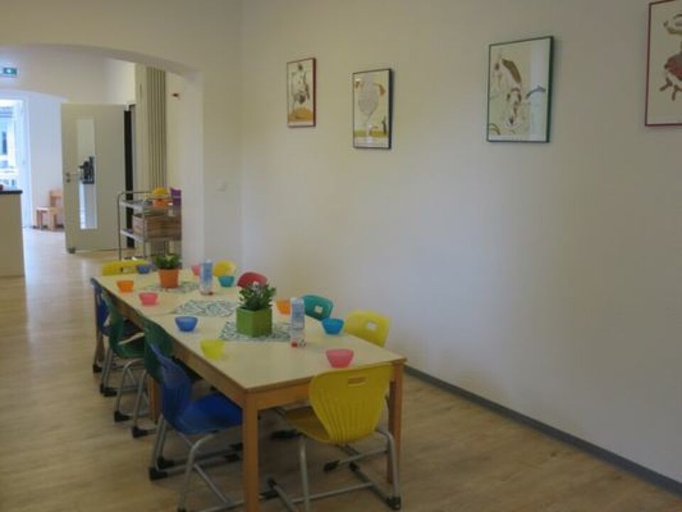 Bistro mit langer, gedeckter Tafel und Stühlen für das Mittagessen der Kinder