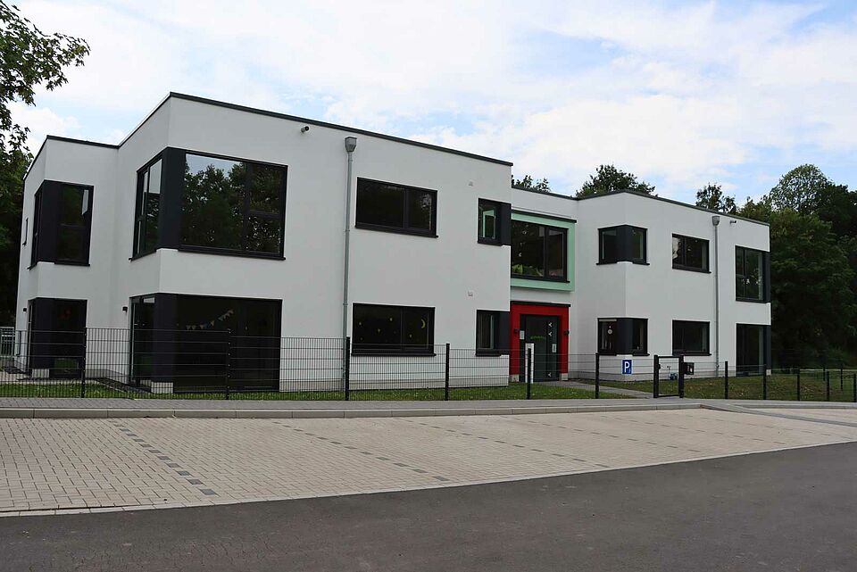 Bild vom Gebäude des DRK-Kindergarten Peppaburg mit Parkplätzen vor dem Eingang