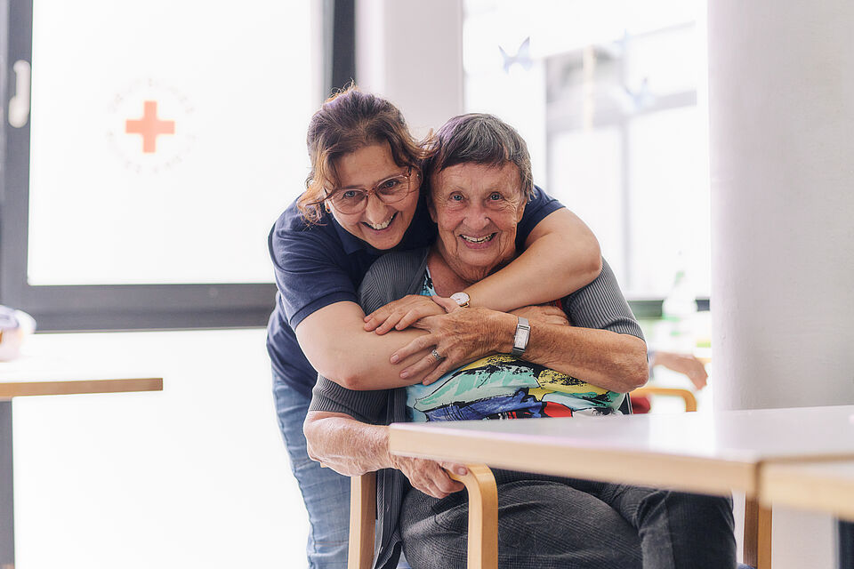 Mitarbeiterin des DRK und Bewohnerin lachen zusammen
