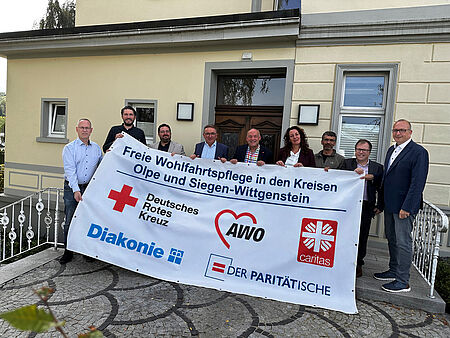 Vertreterinnen und Vertreter der Arbeitsgemeinschaft der Freien Wohlfahrtspflege aus den Kreisen Olpe und Siegen-Wittgenstein stehen hinter einem Banner