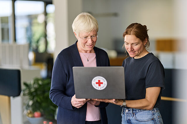 Zwei Frauen unterschiedlicher Generationen schauen gemeinsam auf einen Laptop mit den Angeboten des DRKs