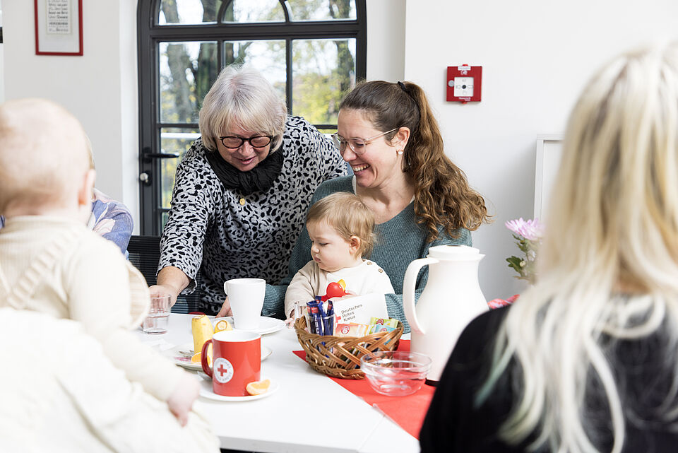 Mehrgenerationenhaus - Mütter mit ihren Babys und Seniorinnen an der Kaffeetafel