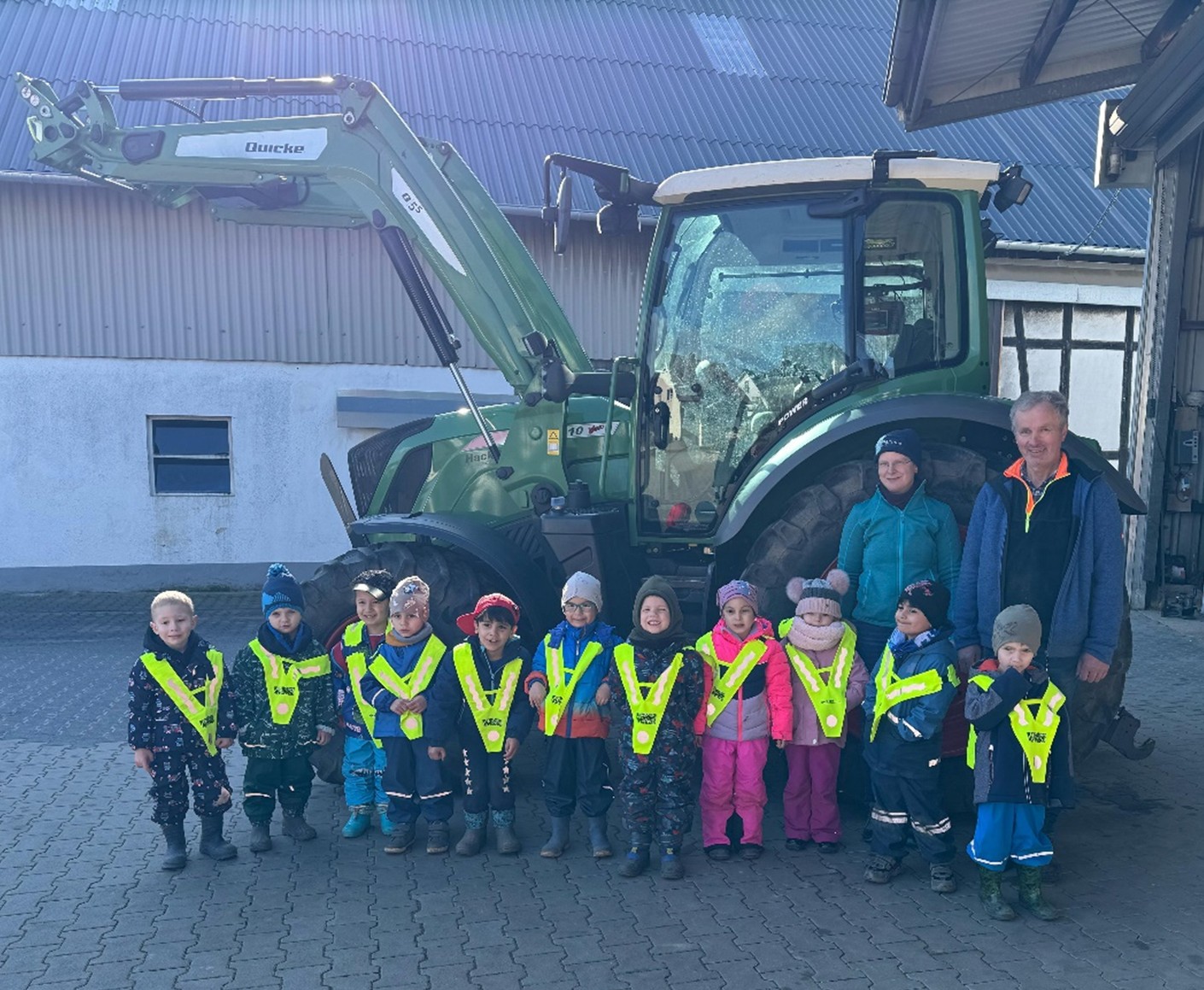 Die Kinder des Sternenlandes haben einen Bauernhof besucht. Kinder stehen vor einem Traktor.